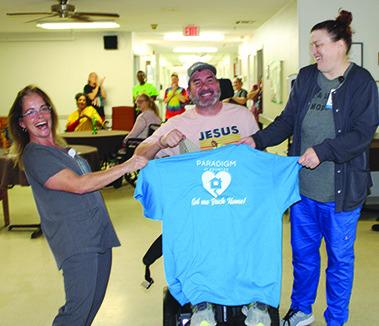 Tony Feagan was given a Paradigm t-shirt, a certificate of completion and a big going away party on March 7 at Paradigm at Kountze. Feagan, who had been told he might never walk again, took rehab at Paradigm, and with the help of Natalie Blackwell, left, and Aline Graham, right, Paradigm therapists, he has been able to walk again with a walker and was released to go home.