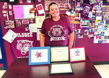 Wendy Rogers, owner of the Tiger Hut, stands behind some of the many awards she and the Tiger Hut have won in the last three years, and in front of a wall with photos, stories and other memorabilia of the Silsbee Tigers.