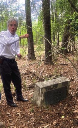 James A. McKim III pulls some brush back from over a marked grave in the Grayburg Black Cemetery. He said trees and limbs grew up over the cemetery after the cemetery was no longer being used.