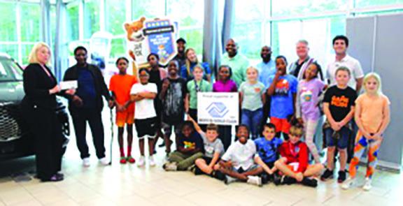 As several children for the Hardin County Boys &amp; Girls Club watch, Karen Herrera, Hyundai Inter-national Business Development manager, presents a check from Hyundai of Silsbee for $5,000 for the club to Bishop L.D. Matthews of the club’s advisory board. Herrera presented the check in the absence of Dale Early, owner of the Hyundai of Silsbee dealership. Photo by Dan Eakin