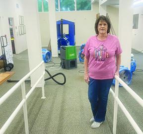 Kathy Johnson, library director, stands at the entrance to the children’s section of the Silsbee Public Library which had to be emptied because of the flooding which occurred both on Monday and Thursday last week.. In background are blowers drying out the floor and lower sides of the section of the library. Dan Eakin Photo