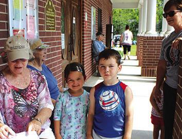 Mary Johnston and others were busy in front of the Kountze Public Library Tuesday morning signing up children for the Summer Reading Program.Above,signing up are Vivi Ann McWilliams and Lincoln McWilliams.