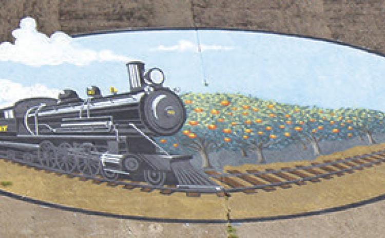 This mural shows a steam engine train pulling freight through Silsbee, with a Satsuma orange grove at the right.Notice the smoke coming out of the top of the engine and the orange trees at the right.