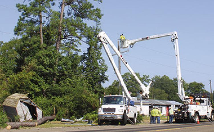 Crews from Bright Star Solutions were working along Hwy 92 Friday morning to repair downed power lines which had left more than 600 homes without power. A sawed up pine tree in lower left of the photo had fallen on the power lines during a brief but strong thunderstorm the night before. Dan Eakin PHoto