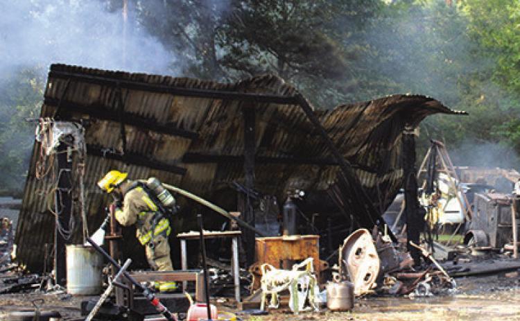 A firefighter puts the finishing touches on putting out a fire after a propane explosion in a shed at 5847 Ben D. Smith Road northwest of Silsbee about 6 p.m. on Tuesday, July 11. At least one vehicle was destroyed. There were no injuries. Photo by Dan Eakin
